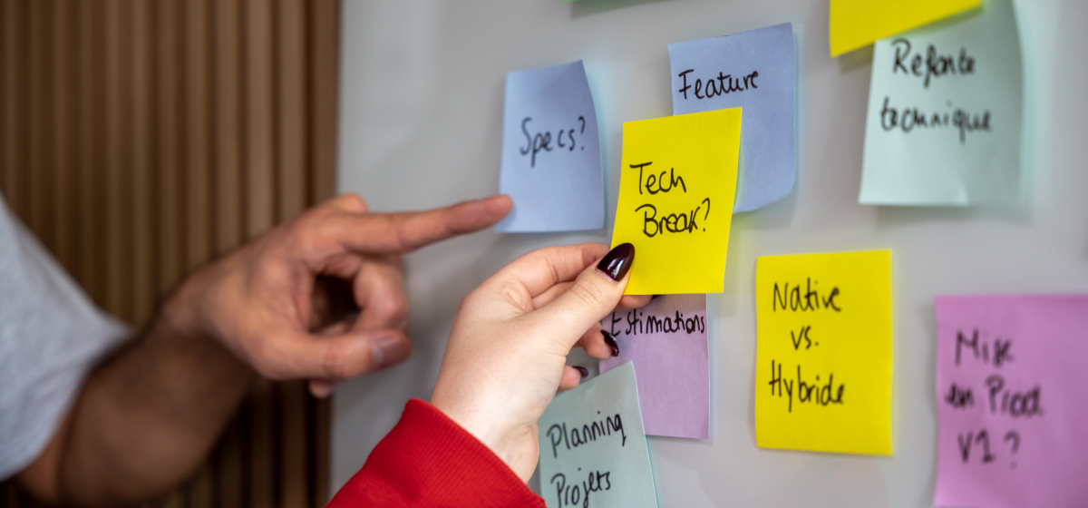 2 people add post-it notes on a whiteboard